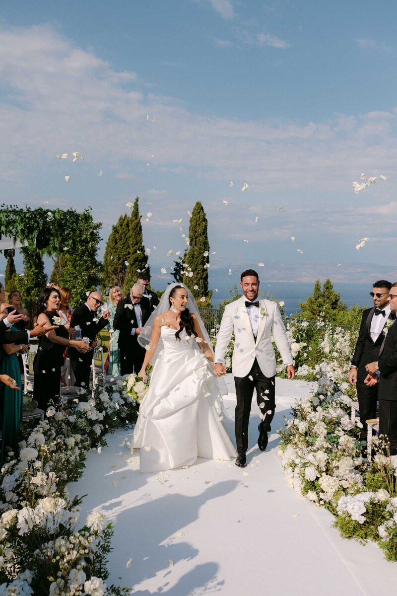 editorial wedding ceremony in Corfu with bride and groom walking through flower aisle