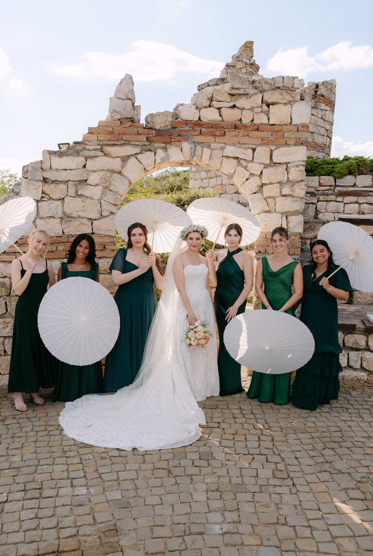 Bride with bridesmaids at Black Sea Rama wedding in Bulgaria, standing beneath the stone amphitheatre arch