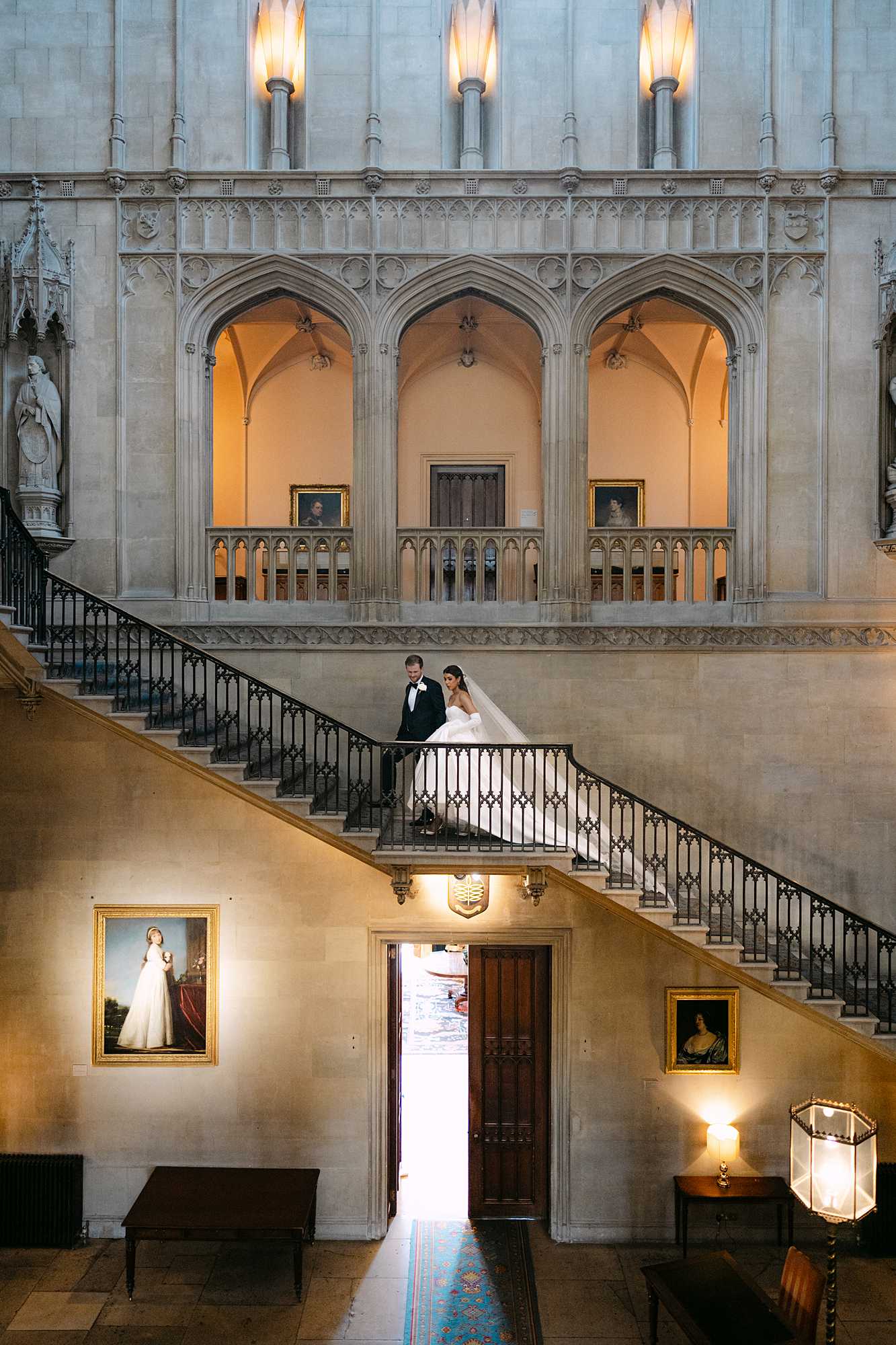 Bride and groom walking up the grand staircase inside Ashridge House during their elegant UK wedding.