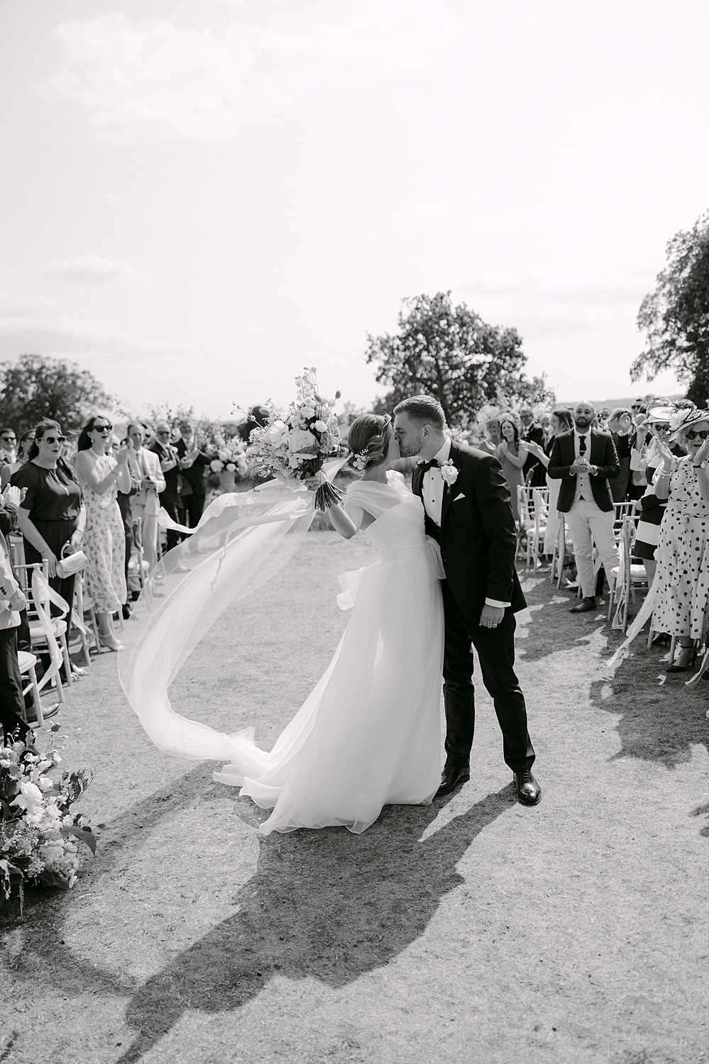 Bride and groom walking back down the aisle together after the ceremony, photographed in black and white.”