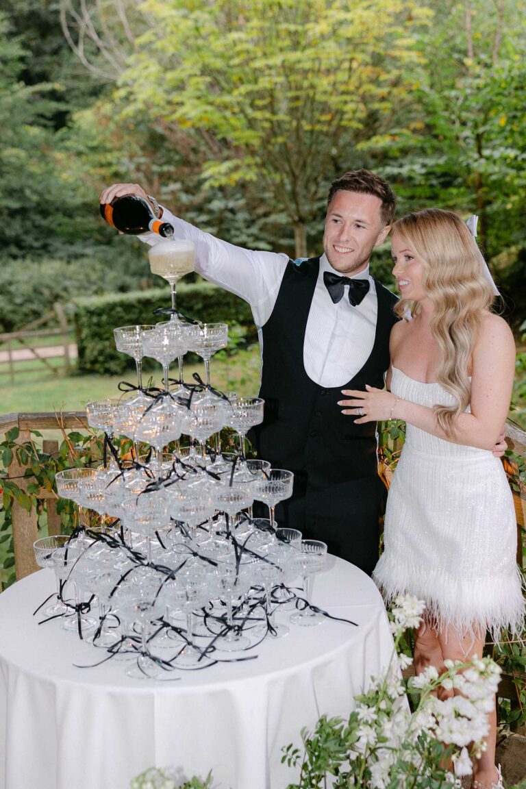 Bride and groom pouring champagne during their wedding at Dewsall Court in Herefordshire