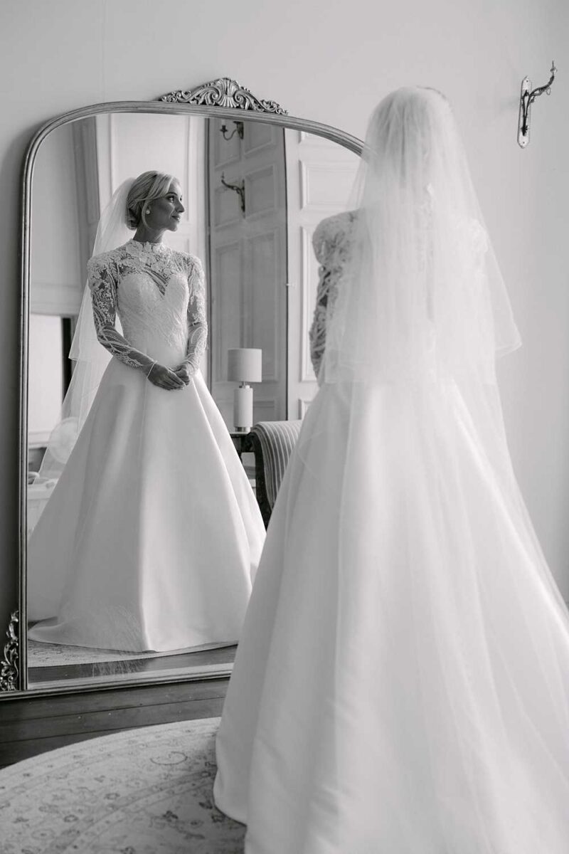 Bride seen in her wedding dress reflected in a mirror at Brympton House