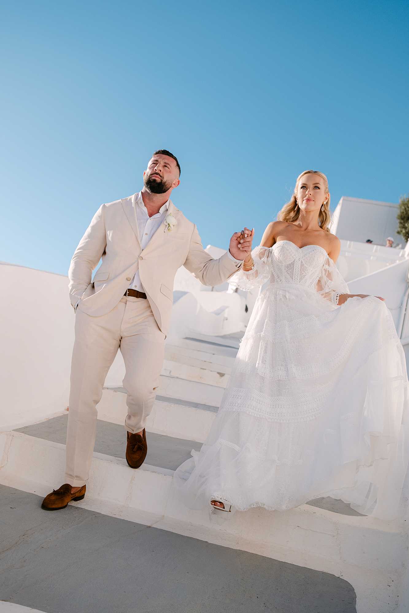 Bride and Groom walk down steps at Dana Villas for thier wedding in Santorini. Photographed by Europe and UK wedding photographer Ross Hurley